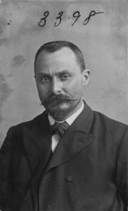 High quality black and white photograph of Vito Cascio Ferro. He is a white man with a full head of short, neatly clipped hair. He has whiskers, a small goatee, and a broad mustache waxed to points. 